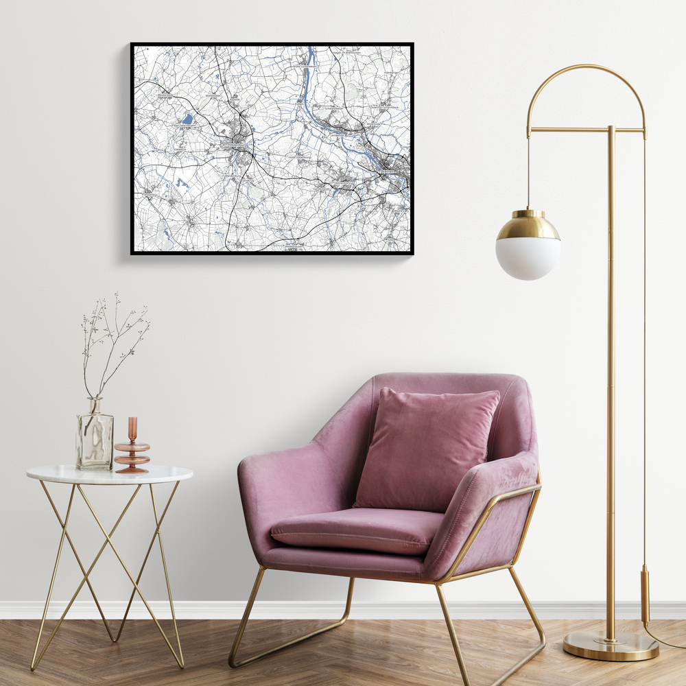 Gepersonaliseerde landkaart in zwarte lijst boven een roze fauteuil, naast een goudkleurige vloerlamp
